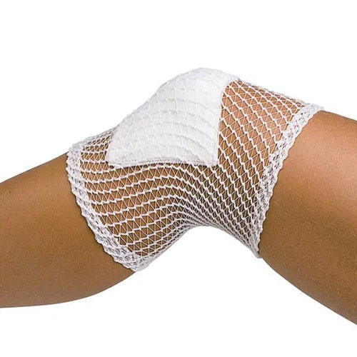 Ein hochelastischer Netzschlauchverband der über ein Knie gestülpt wurde und auf der Kniescheibe ein Tupfer mit dem Netzschlauchverband festgehlaten wird.jpg